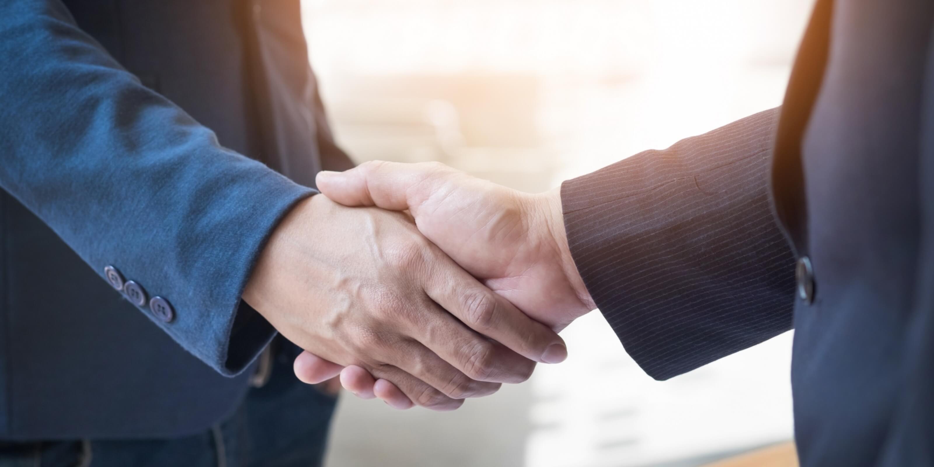 Two people shaking hands with a blurred background
