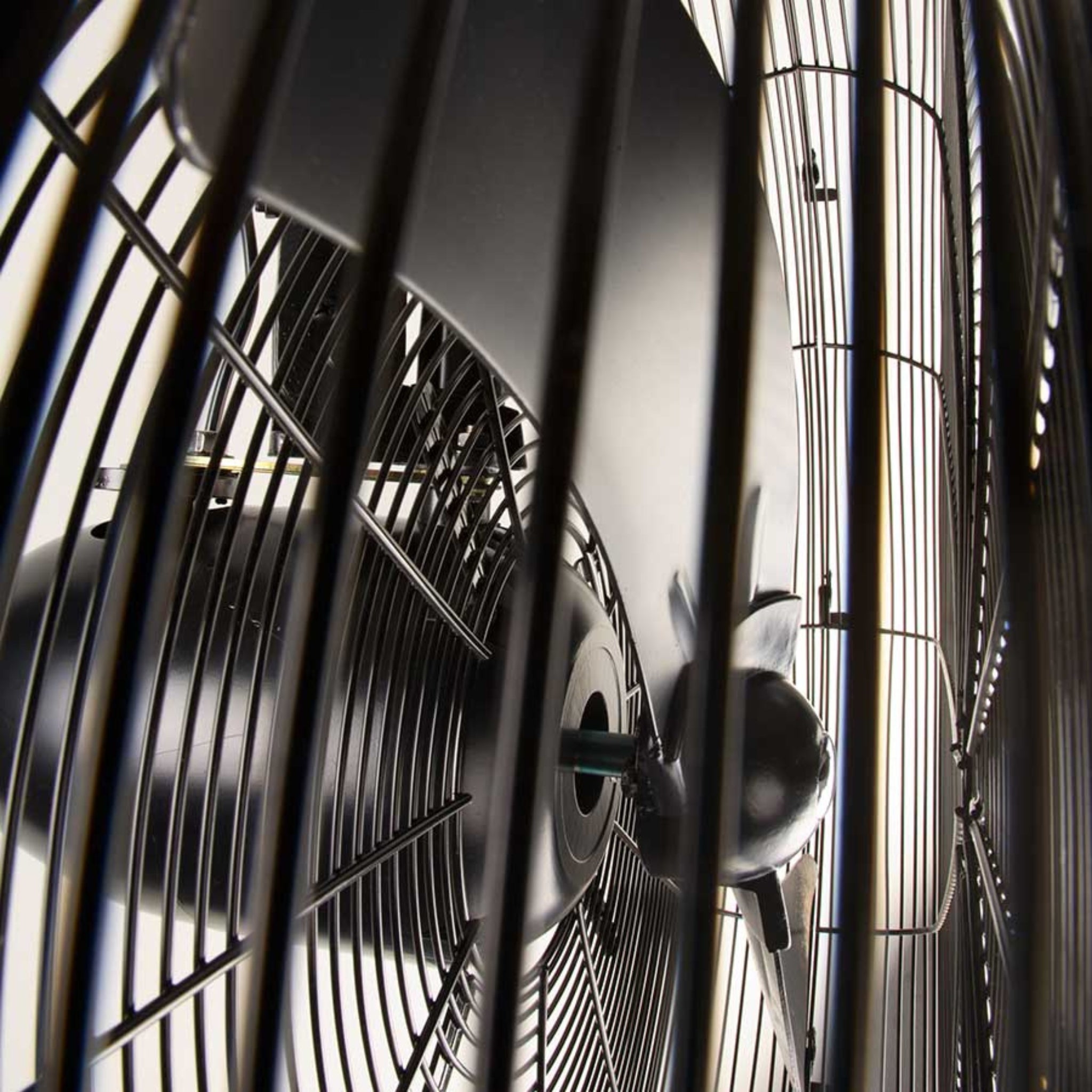 Close-up of 26-Inch (650mm) industrial wall-mounted fan showing high-velocity blades behind a heavy-duty steel safety grill, designed for powerful, all-metal commercial cooling in warehouses and workshops.