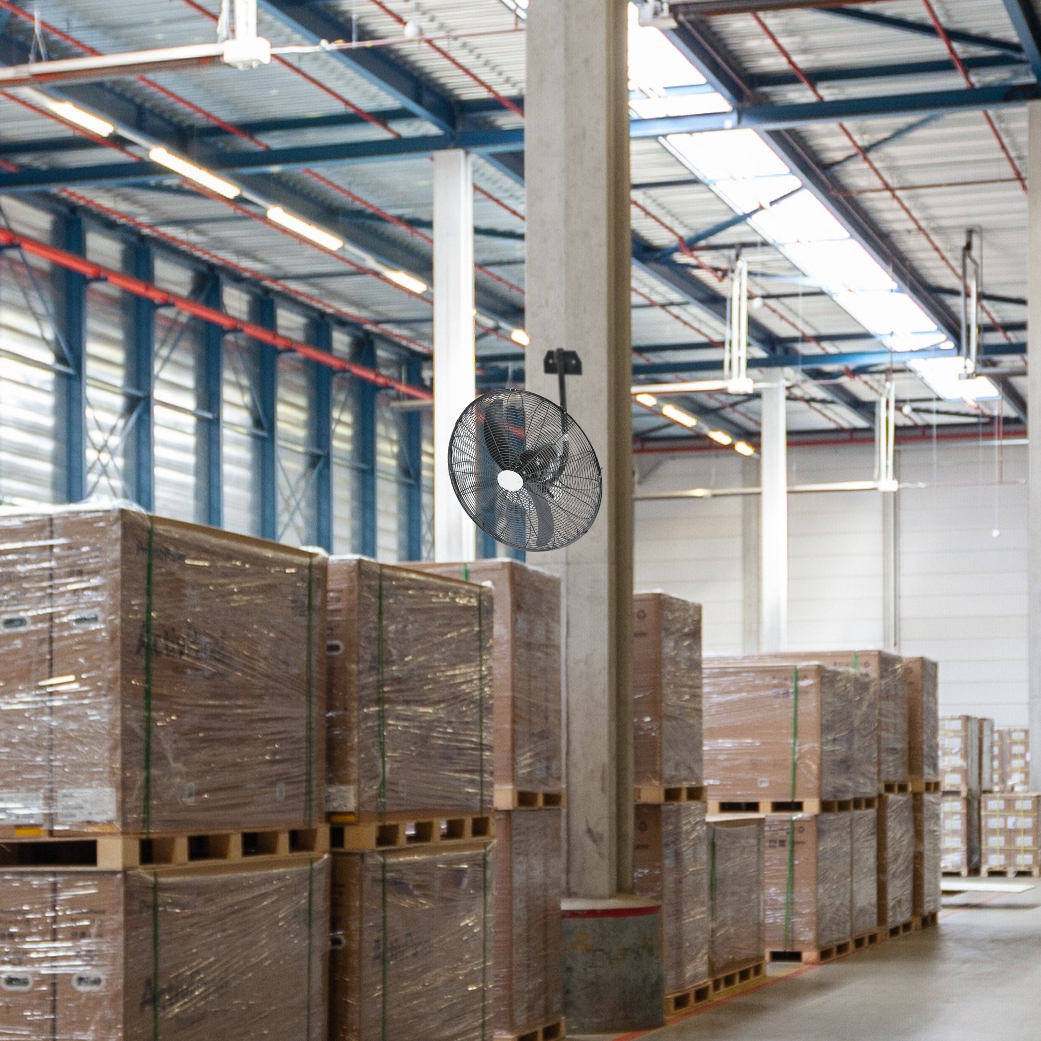 Hydor Hi-Flow 26-Inch (650mm) Industrial Wall-Mounted Fan delivering wide airflow coverage over pallet-stacked aisles in a commercial warehouse setting.